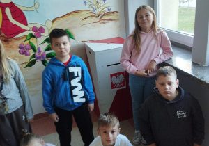 Uczniowie stoją przy urnie do głosowania