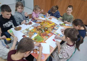 Uczniowie przy stoliku tworzą prace plastyczne