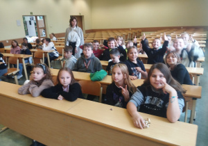 Dzieci siedzą w ławkach na wykładzie