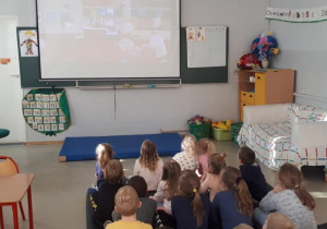Dzieci siedzą na materacu i oglądają film edukacyjny o tolerancji