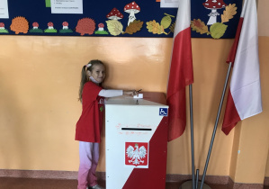 Dziewczynka wrzuca głos do urny wyborczej