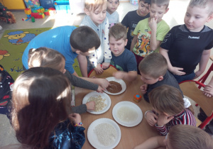 Dzieci za pomocą zmysłu dotyku poznają różne kasze, ryż i płatki owsiane