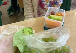 Zdjęcie przedstawia uczennicę podczas drugiego śniadania, w śniadaniówce ma kolorowe owoce i warzywa