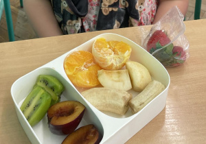 Zdjęcie przedstawia uczennicę podczas drugiego śniadania, w śniadaniówkach ma kolorowe owoce i warzywa oraz smaczne musy owocowe