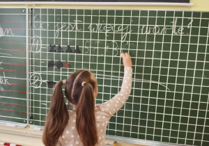 Dziewczynka zapisuje na tablicy działanie.