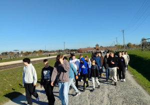 Uczniowie spacerują wzdłuż rampy kolejowej w obozie Auschwitz II - Birkenau