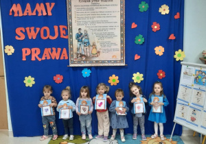 Dzieci z przedszkola, z grupy RYBKI , na tle tablicy informującej o Dniu Praw Dziecka