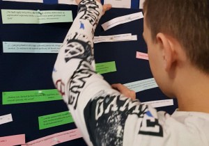 Uczeń przypina do tablicy karteczkę z mottem