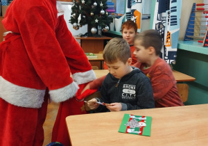 Uczeń przebrany za Św. Mikołaja rozdaje prezenty