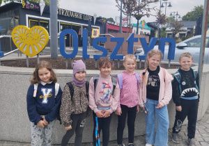 Uczennice stoją przy napisie Olsztyn