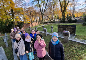 Dzieci stoją przy grobach na cmentarzu