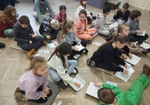 Dzieci rozwiązują zadania z książeczki