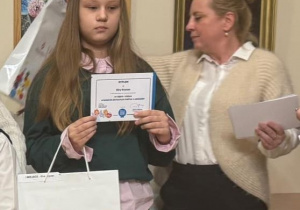 Uczennica stoi z nagrodami